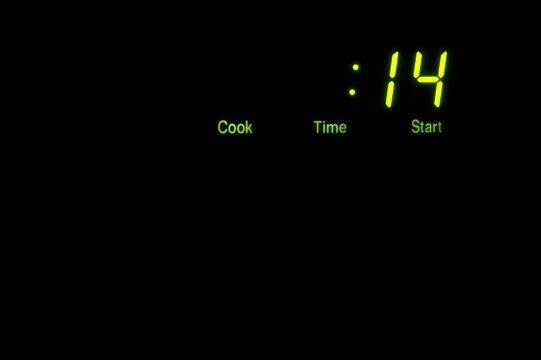 LED display panel on a microwave oven with copy space on a black background - Powered by Adobe