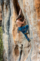 male climber.  strong muscular male rock climber climbs a vertical rock and makes great efforts to...
