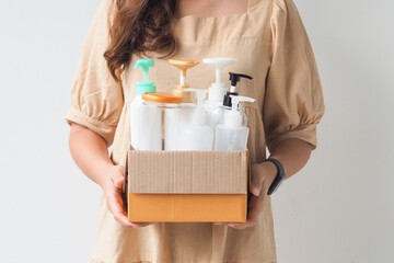 Woman hand holding box of plastic bottles and jar for refill liquid soap, shampoo and other...