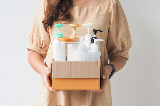 Woman hand holding box of plastic bottles and jar for refill liquid soap, shampoo and other products. Zero waste. Reuse reduce recycle concept.