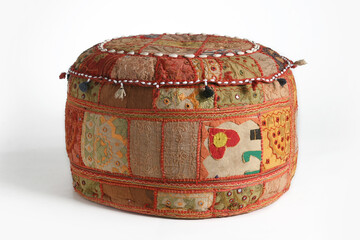 Colorful patchwork pouf with embroidered details and tassels, isolated on white background