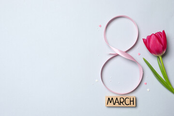 8 March, International Women's Day. Figure eight made of pink ribbon with beautiful tulip on a gray background. Space for text