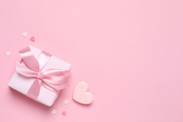 Beautiful composition with gift box and pink hearts on color background