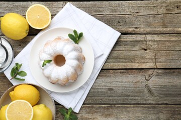 Tasty lemon cake with powdered sugar, fresh fruits and mint on wooden table, flat lay. Space for text