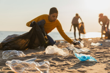 Earth day. Volunteers activists collects garbage cleaning of beach coastal zone. Woman mans with...