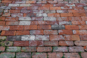 Brick wall with a lot of cracks and dirt. The wall is brown and gray. There are many bricks on the wall