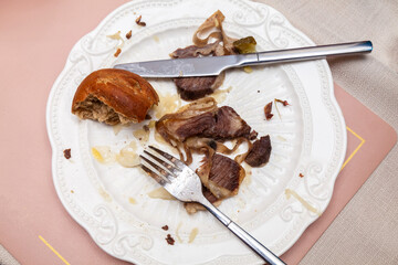A plate with leftover food with a fork and knife on it.