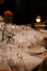 The waiter pours expensive champagne in the evening at the restaurant