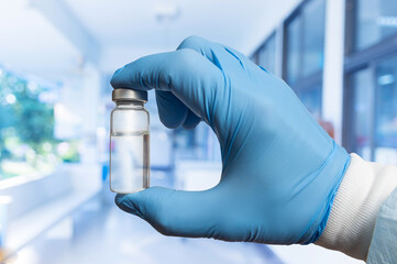 Hand holding a clear vial in a laboratory environment showcasing scientific research and medical preparation