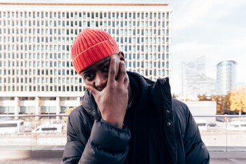 Man wearing a red beanie and dark coat in an urban setting