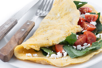 Stuffed omelette with tomatoes and spinach isolated on white background. Close up
