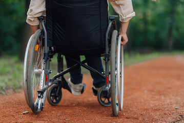 Naklejka premium Unrecognizable person moving on wheelchair in park: overcoming obstacles and enjoying nature