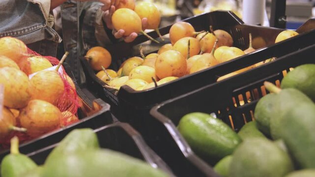 Young Woman Choosing passion fruits (granadilla, passiflora ligularis) in Grocery Store. Concept of healthy food, bio, vegetarian, diet. Selective focus