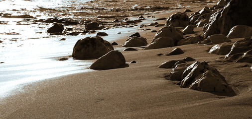 Serene coastal landscape at sunrise with smooth rocks and gentle waves