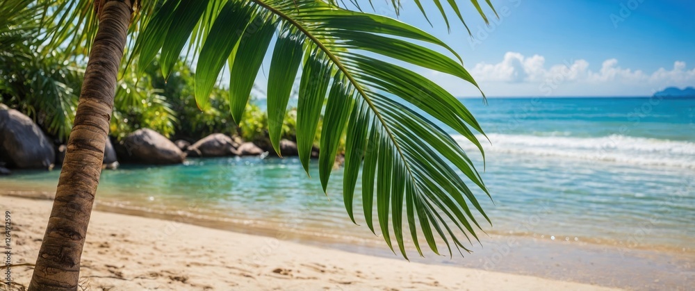 Poster tropical beach scene with palm leaf in foreground and calm blue ocean under clear sky with fluffy cl