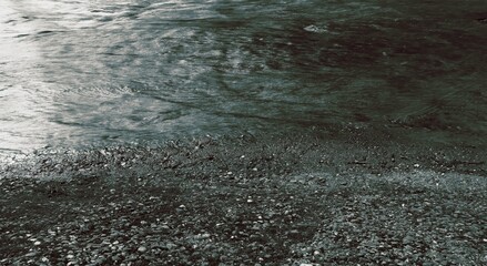 Rippling water meets pebble beach on a cloudy day