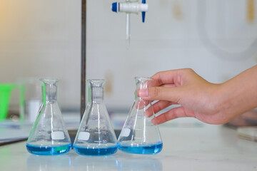 Close-up of a student performing an acid-base titration experiment. Concept of chemistry lab, science, experiment, skills, learning.