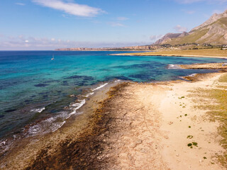 Aerial drone view of Macari (Makari), Sicily. Crystal clear turquoise waters, rugged cliffs, golden sandy beaches. A serene natural landscape with Mediterranean charm near San Vito lo Capo.