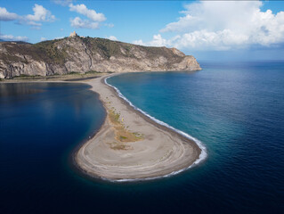 Aerial drone view of Laghetti di Marinello, natural reserve in Sicily, Italy. Sand strip with crystal clear turquoise lagoons, lush Mediterranean vegetation, below a cliff and Tindari Sanctuary.