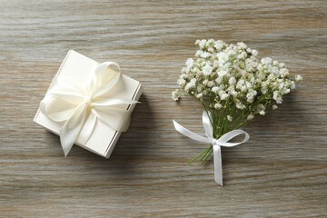 Top view photo with gypsophila flowers and gift box on wooden background 