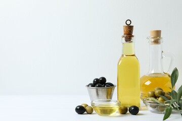 Bottles of fresh olive oil and olives with leaves on the table 