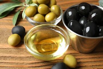 Bowl of fresh olive oil and olives with leaves on the table