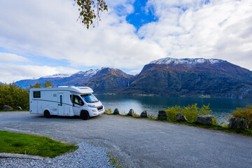 A motorhome parked by the serene Lustrafjorden in South Norway, with stunning mountains and a waterfall in the background. © Alberto Gonzalez 