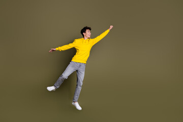 Confident young male in casual clothing posing on a khaki background exuding youthful energy and...