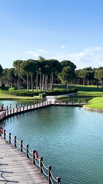 Scenic golf course with island green surrounded by water and wooden bridge in Belek, Turkey