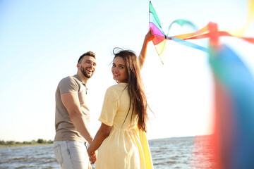 Happy couple playing with kite near sea. Spending time in nature