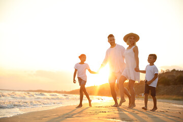 Happy family on sandy beach near sea at sunset
