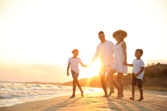 Happy family on sandy beach near sea at sunset - Powered by Adobe