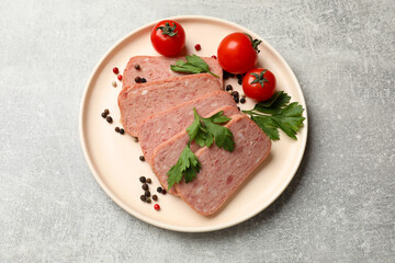Pieces of tasty canned meat, parsley, peppercorns and tomatoes on grey textured table, top view