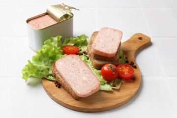 Tasty canned meat, bread, tomatoes, spices and lettuce on white tiled table