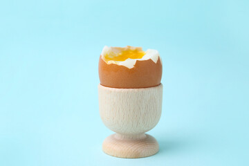 Soft boiled egg in eggcup on light blue background, closeup
