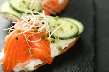 Delicious bruschette with salmon, cream cheese and cucumber on grey table, closeup