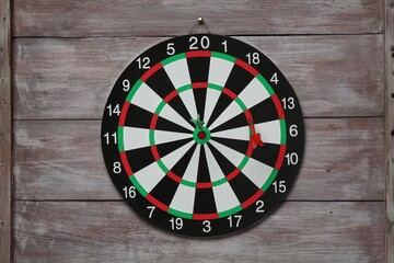 One dart board with colorful arrows on wooden rustic background