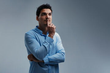 Pensive businessman is thinking with finger on lips looking up