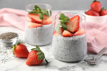 Delicious chia pudding with strawberries and mint on white marble table, closeup