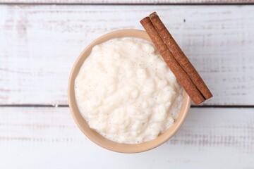 Tasty rice pudding with cinnamon on white wooden table, top view