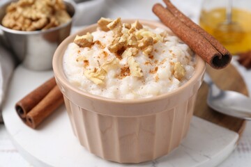 Tasty rice pudding with cinnamon served on white wooden table, closeup