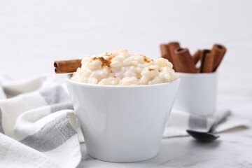 Tasty rice pudding with cinnamon served on white table, closeup
