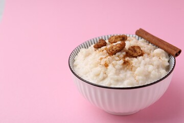 Delicious rice pudding with cinnamon and cashew nuts on pink background, closeup. Space for text