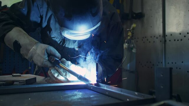 Skilled craftsman with a protective helmet and safety gear, carefully welding together metal pieces to create a sturdy construction, close up shot.