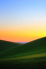 Obraz premium Rolling Green Hills Under a Vibrant Sunset Sky Serene Landscape with Distant Mountains