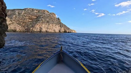 A boat approaches the Blue Grotto in Malta, surrounded by limestone cliffs and deep blue waters. A popular tourist destination known for its sea caves and crystal-clear reflections.