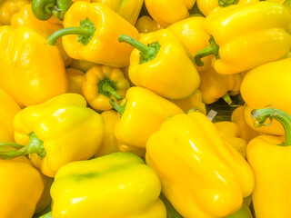 Yellow fresh peppers lie in a basket on the counter in a store