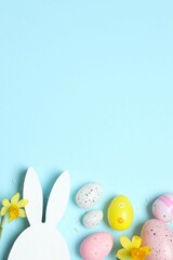 Happy Easter. Colorful eggs, yellow flowers and Easter bunny ears on a pastel color background, space for text or advertising
