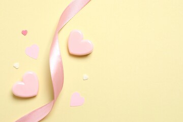 Beautiful composition with pink hearts and silk ribbon on color background
