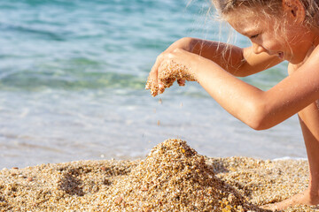 Caucasian child playing with sand on sea beach